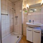 Shower cabin with shower head, sink, and mirror on the wall.