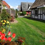 House with thatched roof, green lawn, and flower beds in the front garden.