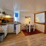 Kitchen with dining area, wooden floor, and white ceiling. Table with chairs and flowers.