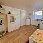 Kitchen with wooden floor, white cabinets, and window with view outside.