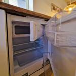 Refrigerator with open door, empty shelves and freezer compartment
