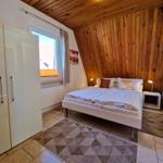Bedroom with double bed, wooden wall, and window.