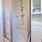 Shower cabin with shower head and adjacent white cabinet