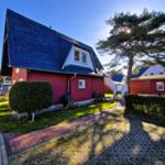 Red house with dark roof and paved path in the front yard