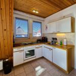 Kitchen with wooden ceiling, white cabinets, and windows with blinds.