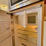 Refrigerator with open door and built-in microwave.
