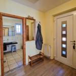 Entrance with wooden floor, mirror, and door with glass panels. View into the bathroom.
