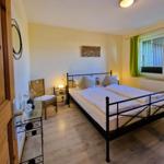 Bedroom with double bed, nightstand, chair, and window with green curtains.