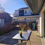 Deck with table, chairs, and grill. Backyard with fence and neighboring house.