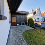 Entrance area with door, walkway, and lawn. Backyard with garden and neighboring house.