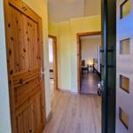 Hallway with wooden doors and light. View into bedroom with bed and table.