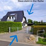 House in second row with driveway and closed gate.