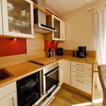 Kitchen with wooden surfaces, integrated dishwasher and oven, and coffee machine.