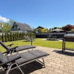 Hinterhof mit Liegestühlen, Grill und Gartenbereich. Blick auf benachbarte Häuser.