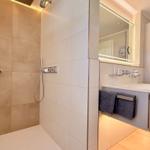 Moderne Dusche mit Handbrause und integriertem Waschbecken mit Spiegel.