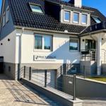 Modernes Haus mit Terrasse und Garten. Eingangsbereich mit Stufen und Geländer.