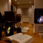 Ein Tisch mit Buch, Tassen und einem Kamin im Hintergrund.
