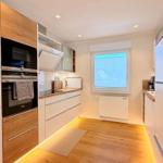 Moderne Küche mit Holzoptik, integriertem Ofen und Küchenzeile.