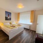 Schlafzimmer mit Doppelbett, Fenster, TV und Stuhl.