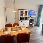 Esszimmer mit Tisch, Stühlen und Fernseher. Durchgang zur Terrasse mit Sitzgelegenheit.