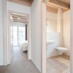 Hallway with bedroom and bathroom. Wooden beams and white walls.