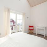 Bedroom with white bed, window, and red chair.