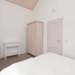 Bedroom with bed, wardrobe, desk, and red chair.