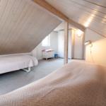 Room with two beds, wooden ceiling, and closet in background.
