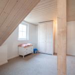 Attic room with wooden ceiling, wardrobe, and window.