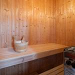 Sauna with wooden walls, bench, and wooden wash bucket.