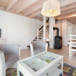Living and dining area with wooden beams, TV, seating, and dining table.