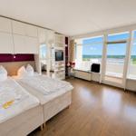 Room with double bed, built-in closet, and large window with view of the landscape.