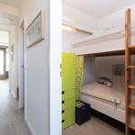 Kinderzimmer mit Hochbett, grünem Schrank und Holzleiter.