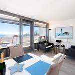 Wohn- und Essbereich mit Meerblick, Sofa, Stühle und Tisch mit Plastikdecken.