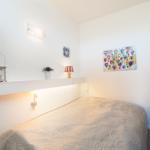 Ein Schlafzimmer mit Bett, Wandregal und Wandbildern.