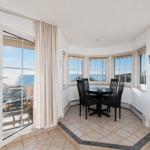 Dining room with sea view and balcony. Black table and chairs.