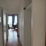 Flur mit Blick in Wohnbereich und Schlafzimmer mit rotem Bett.