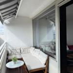 Terrasse mit Sitzgruppe, Tisch und Sonnenschutz. Durchgang ins Innere.