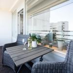 Balcony with table, two chairs, plants, and a wine bottle.