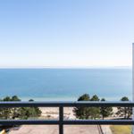 View from balcony over sea, beach, and high-rise building