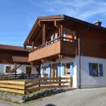 Wooden house with balcony, blue shutters, and garden area
