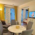 Living area with dining table, sofa, and TV. Passage to bedroom. Yellow curtains.