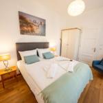 Schlafzimmer mit Doppelbett, Nachttisch, Stuhl und Wandbild.