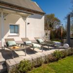 Terrasse mit Liegestühlen, Whirlpool und Garten. Hinterhof mit Bäumen und Grasfläche.