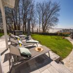 Terrasse mit Liegestühlen, Whirlpool und Blick auf den Garten und die Landschaft.