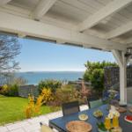 Terrasse mit Blick auf das Meer, gedeckter Tisch mit Obst und Getränken.