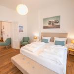 Schlafzimmer mit Doppelbett, zwei Nachttischen, zwei Sesseln und einem Fenster.