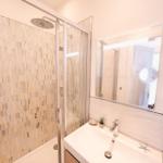Badezimmer mit Dusche, Waschbecken und Spiegel