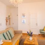 Wohnzimmer mit Sofa, Sessel, Couchtisch und Kronleuchter.