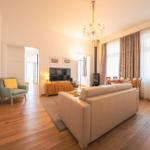 Wohnzimmer mit Sofa, Fernseher und Esstisch. Holzboden und große Fenster.